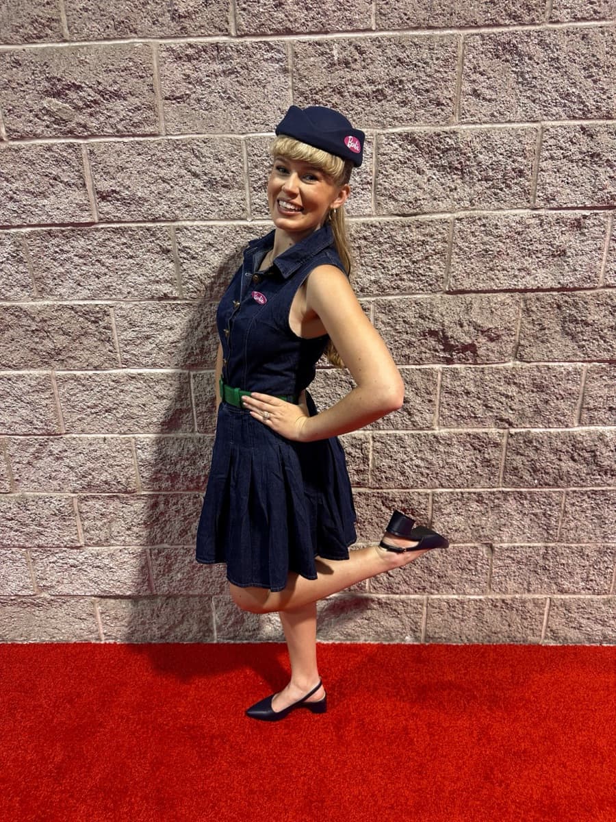 Kayla in a navy dress and cap on a red carpet at a D23 event
