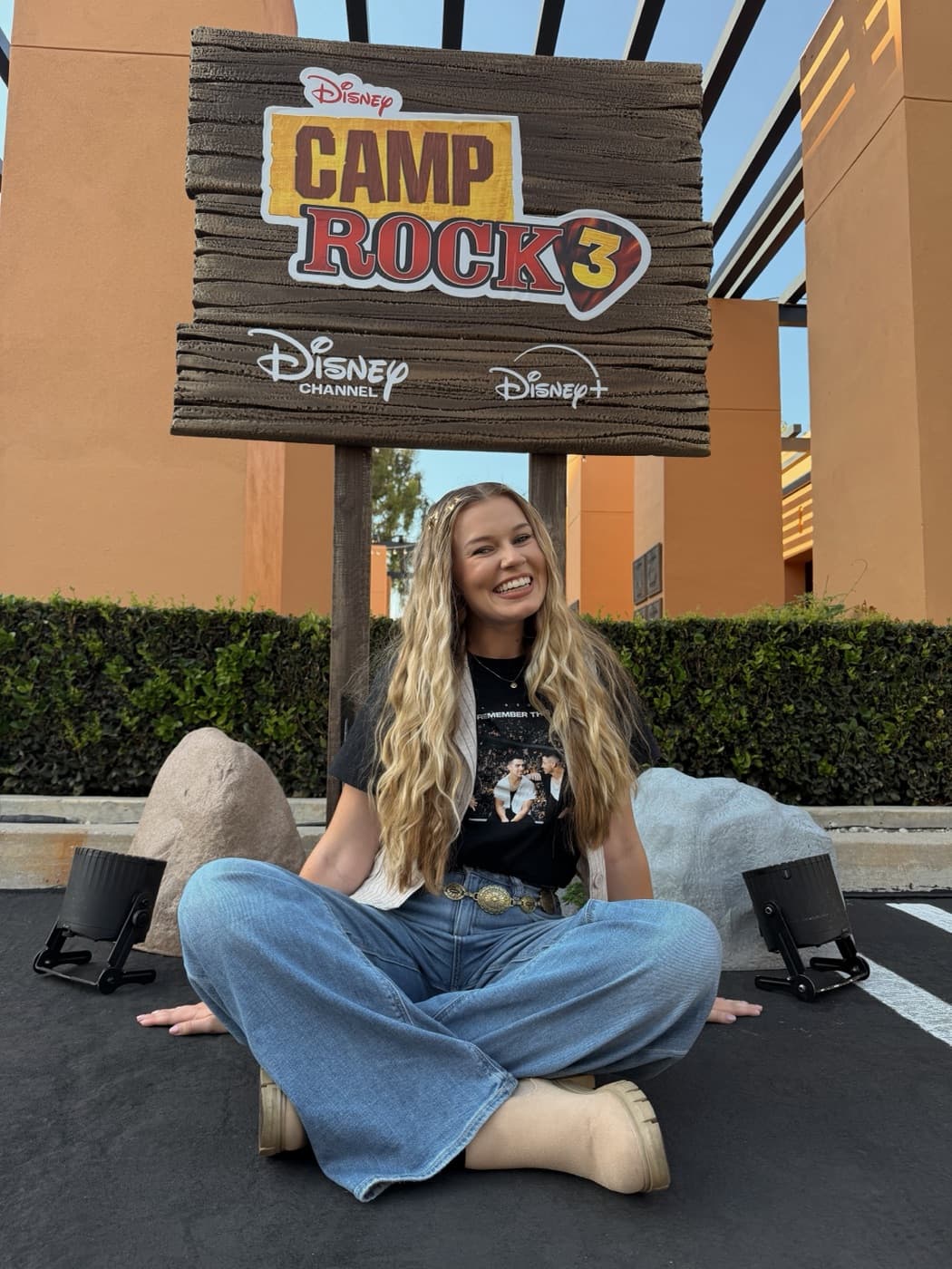 Kayla sitting beneath the Camp Rock 3 sign on the Disney Studio Lot