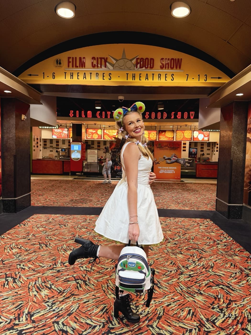Kayla in Toy Story ears and a white dress in a movie theater lobby